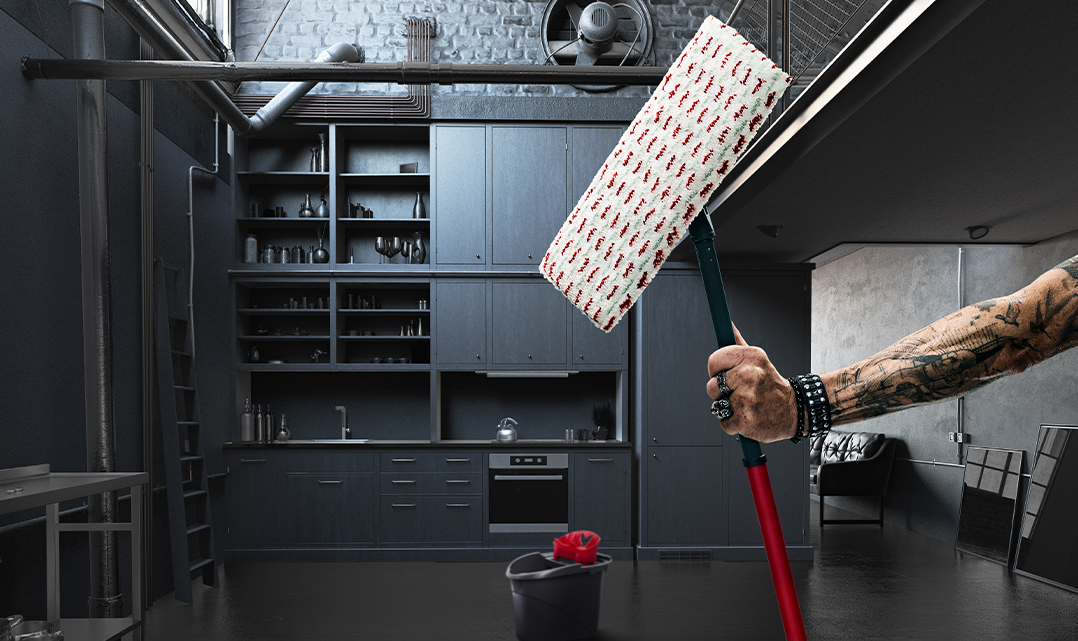 En tatoveret arm med et nittearmbånd holder en Viledamoppe i et sort køkken.